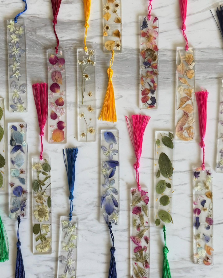 Decorative bookmarks with floral and tassel designs on a textured surface